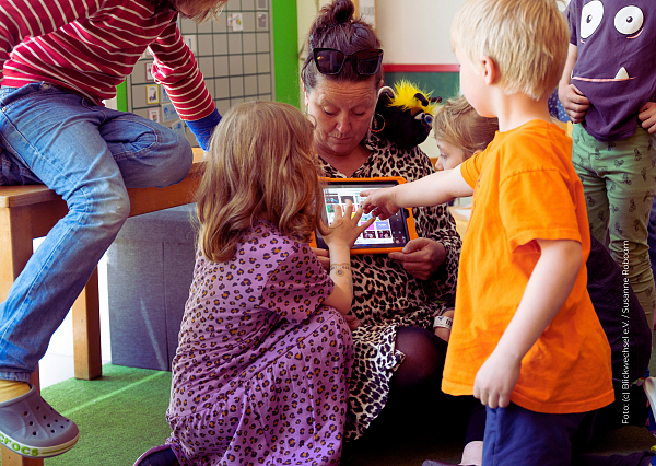 Frau mit Tablet, die Kindern etwas zeigt 