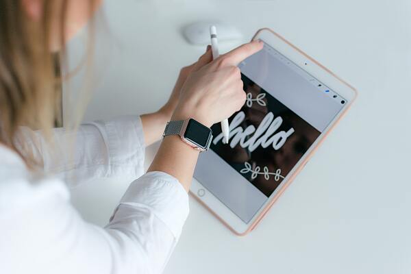 Eine Frau im Anschnitte, deren Hand auf dem iPad malt.