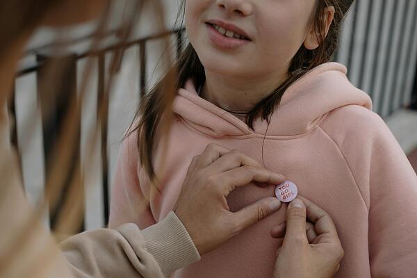 Ein Mädchen, das einen Pin an den Pullover gepinnt bekommt