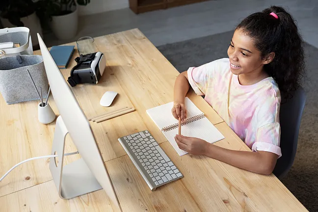 Eine Schülerin, die vor ihrem Computer sitzt und dort digital an Lernveranstaltungen teilnimmt 