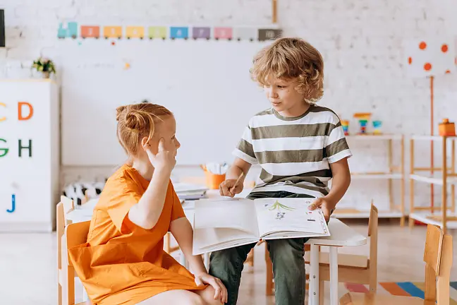 Eine Schülerin und ein Schüler, die sich ein Buch ansehen
