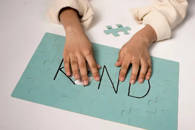 Kind, das puzzlet. Du siehst nur die Hände auf dem Puzzle liegen.